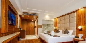 A spacious and modern bedroom suite at a luxury rehab facility, featuring elegant wood paneling, a king-sized bed, flat-screen TV, and high-end accommodations designed for comfort during recovery.